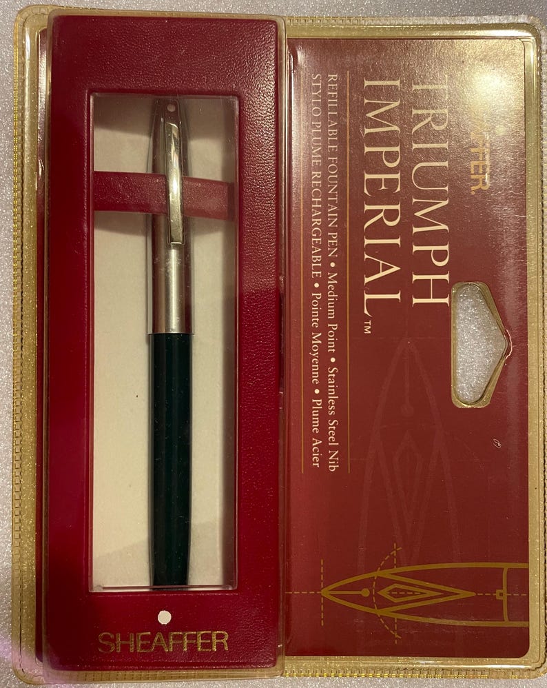 May include: A black and silver Triumph Imperial refillable fountain pen with a medium point stainless steel nib. The pen is in a red and gold box with the brand name "Sheaffer" printed on the bottom.
