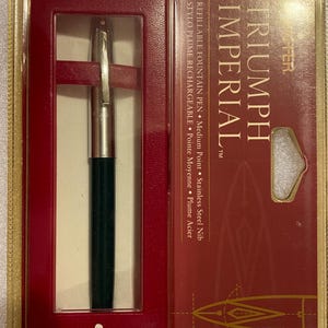 May include: A black and silver Triumph Imperial refillable fountain pen with a medium point stainless steel nib. The pen is in a red and gold box with the brand name "Sheaffer" printed on the bottom.