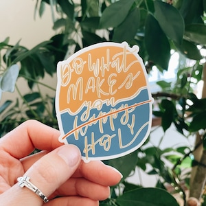 May include: A sticker with a blue and orange background and the text "Do what makes you happy, not holy" with the word "happy" crossed out.