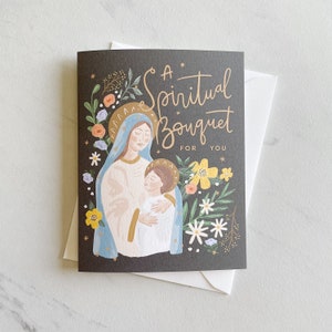 May include: A black card with a gold inscription that reads "A Spiritual Bouquet For You". The card features a colorful illustration of Mary and Jesus surrounded by flowers.