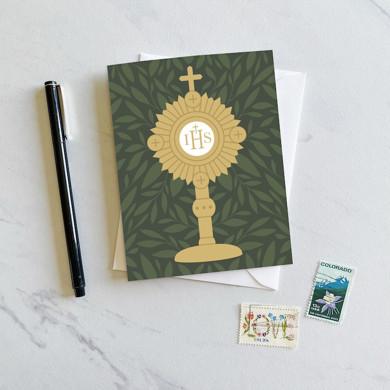 Pode incluir: Um cart&atilde;o verde com um monograma dourado das letras "IHS" rodeado por um desenho de raios de sol. O monograma est&aacute; em um pedestal com uma cruz no topo. O fundo &eacute; um padr&atilde;o de folhas verdes.