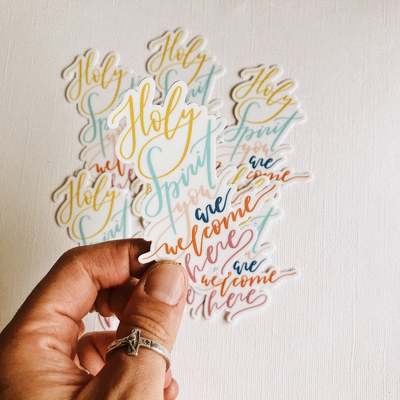 K&ouml;nnte beinhalten: Ein Satz bunter Aufkleber mit dem Schriftzug "Holy Spirit you are welcome here" in einer kursivschriftlichen Schrift.