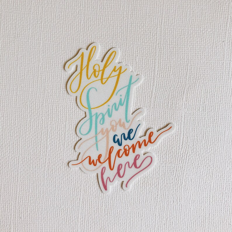 K&ouml;nnte beinhalten: Ein bunter Aufkleber mit den Worten "Holy Spirit you are welcome here" in kursivschrift.