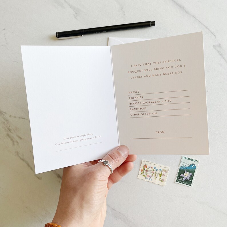 May include: A beige card with a handwritten message that reads "I pray that this spiritual bouquet will bring you God's graces and many blessings." The card has a list of items including "Masses, Rosaries, Blessed Sacrament Visits, Sacrifices, Other Offerings." The card also has the words "From" and "Colorado" printed on it.