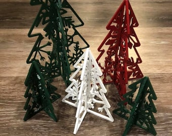 May include: Five wooden Christmas tree decorations in various sizes. The trees are decorated with snowflake cutouts. The trees are green, red, and white.