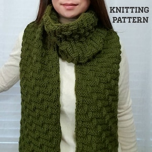 May include: A green knitted scarf with a textured pattern. The scarf is folded and draped around a person's neck.  KNITTING PATTERN.