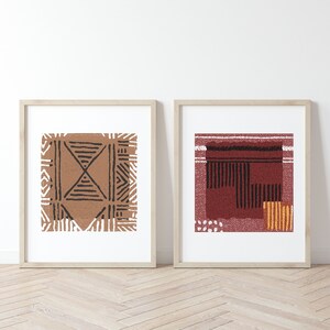 May include: Two framed prints with abstract geometric patterns. The print on the left features a brown and black geometric pattern. The print on the right features a red, black, and yellow geometric pattern.
