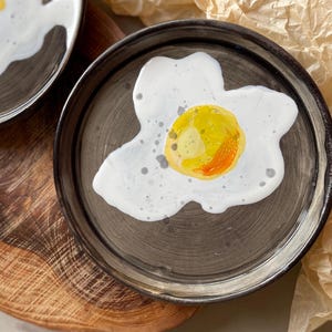 Handgjord keramisk tallrik med äggmotiv med solsidan uppåt, serveringsfat för frukost
