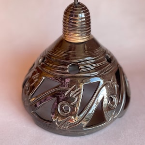 May include: Black ceramic lampshade with a decorative cutout design. The shade has a glossy finish and a textured top.