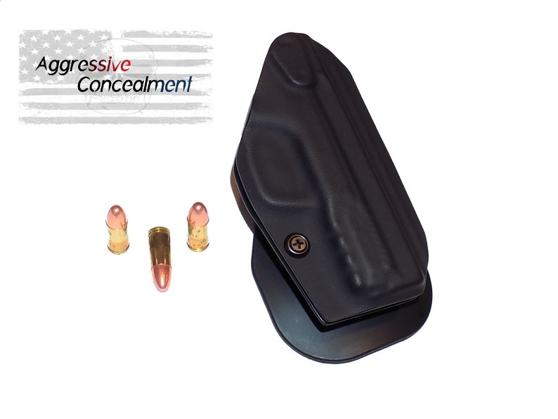 May include: A black polymer holster with a metal clip. The holster is designed to hold a handgun. Three bullets are also shown in the image.