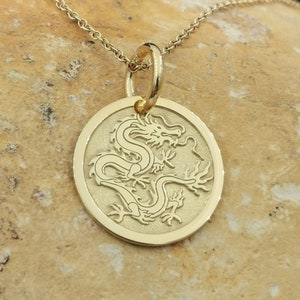 Chinese Dragon engraved, circular,
solid gold pendant 14k,
the size is 0,5 iches / 12,7 millimeter.
Thickness 0,5 milimiters.
The hoop on top is circular and gold as well.
 The finish of the pendant in shinny.