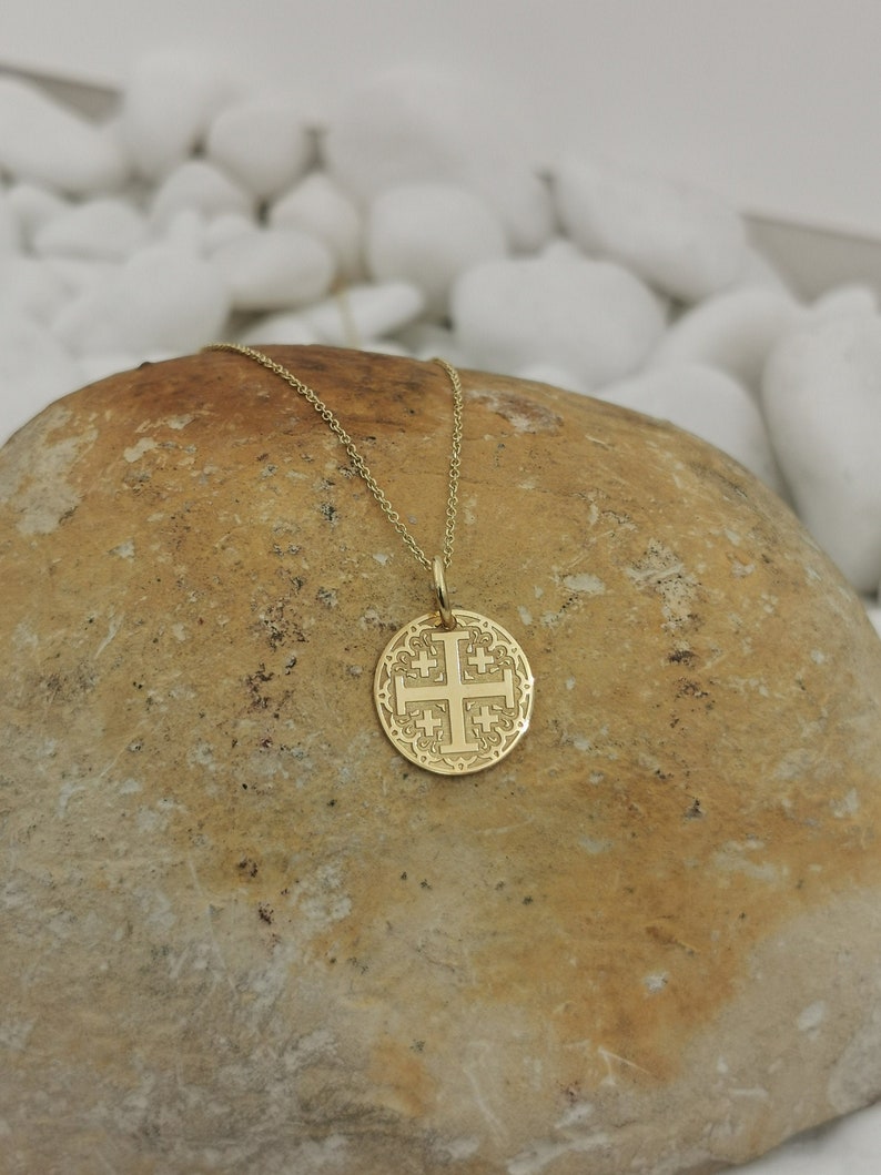 Jerusalim cross engraved, circular,
solid gold pendant 14k,
the size is 0,5 iches / 12,7 millimeter.
Thickness 0,5 milimiters.
The hoop on top is circular and gold as well.
 The finish of the pendant in shinny.