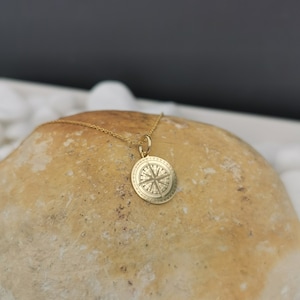 Compass engraved, circular,
solid gold pendant 14k,
the size is 0,5 iches / 12,7 millimeter.
Thickness 0,5 milimiters.
The hoop on top is circular and gold as well.
 The finish of the pendant in shinny.