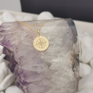 Compass engraved, circular,
solid gold pendant 14k,
the size is 0,5 iches / 12,7 millimeter.
Thickness 0,5 milimiters.
The hoop on top is circular and gold as well.
 The finish of the pendant in shinny.