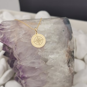 Compass engraved, circular,
solid gold pendant 14k,
the size is 0,5 iches / 12,7 millimeter.
Thickness 0,5 milimiters.
The hoop on top is circular and gold as well.
 The finish of the pendant in shinny.