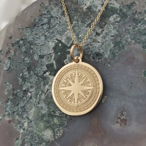 Compass engraved, circular,
solid gold pendant 14k,
the size is 0,75 iches / 19,1 millimeter.
Thickness 0,5 milimiters.
The hoop on top is circular and gold as well.
 The finish of the pendant in shinny.