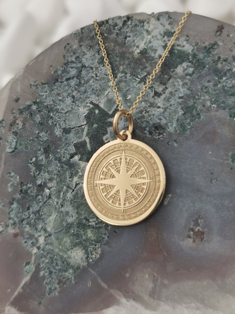 Compass engraved, circular,
solid gold pendant 14k,
the size is 0,75 iches / 19,1 millimeter.
Thickness 0,5 milimiters.
The hoop on top is circular and gold as well.
 The finish of the pendant in shinny.
