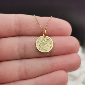 Chinese Dragon engraved, circular,
solid gold pendant 14k,
the size is 0,5 iches / 12,7 millimeter.
Thickness 0,5 milimiters.
The hoop on top is circular and gold as well.
 The finish of the pendant in shinny.