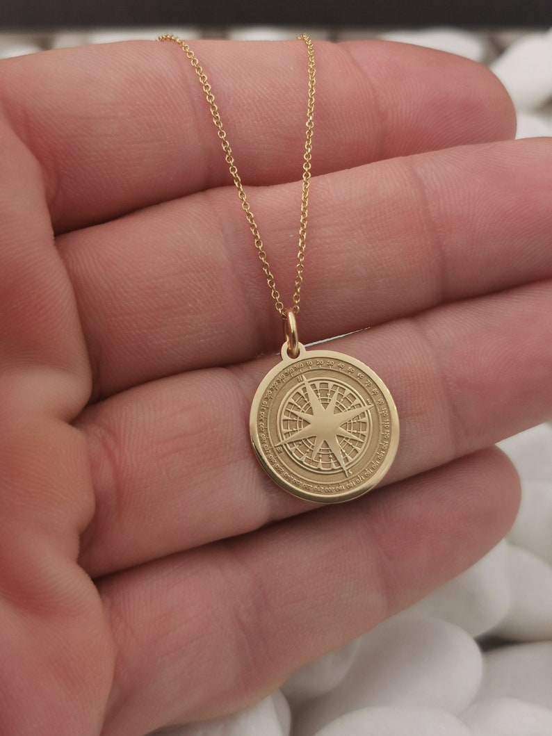 Compass engraved, circular,
solid gold pendant 14k,
the size is 0,75 iches / 19,1 millimeter.
Thickness 0,5 milimiters.
The hoop on top is circular and gold as well.
 The finish of the pendant in shinny.