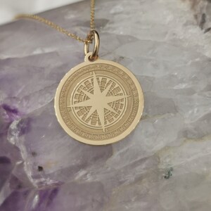 Compass engraved, circular,
solid gold pendant 14k,
the size is 0,75 iches / 19,1 millimeter.
Thickness 0,5 milimiters.
The hoop on top is circular and gold as well.
 The finish of the pendant in shinny.