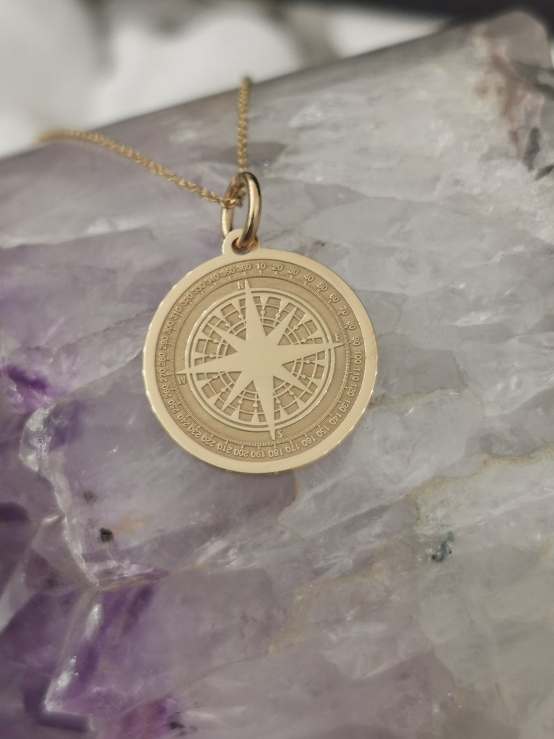 Compass engraved, circular,
solid gold pendant 14k,
the size is 0,75 iches / 19,1 millimeter.
Thickness 0,5 milimiters.
The hoop on top is circular and gold as well.
 The finish of the pendant in shinny.
