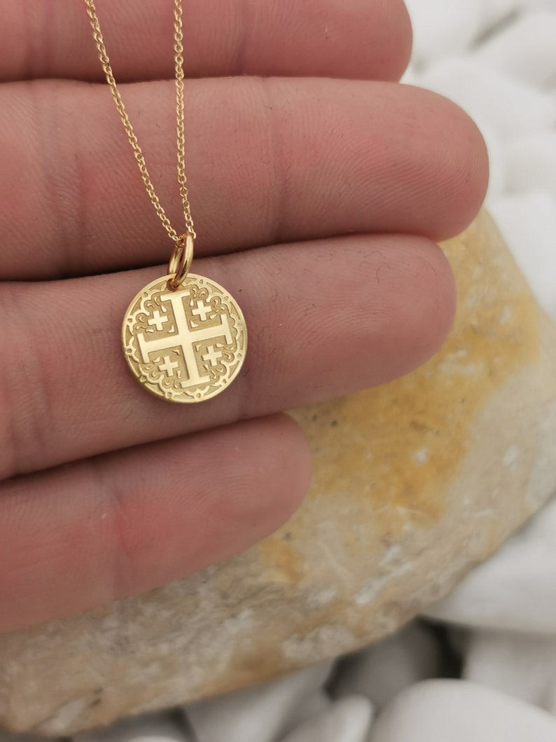 Jerusalim cross engraved, circular,
solid gold pendant 14k,
the size is 0,5 iches / 12,7 millimeter.
Thickness 0,5 milimiters.
The hoop on top is circular and gold as well.
 The finish of the pendant in shinny.