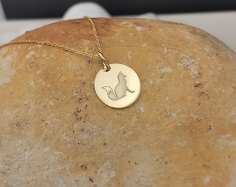Może przedstawiać: Złoty naszyjnik z łańcuszkiem i okrągłym wisiorem z grawerowanym siluetowym wizerunkiem lisa.