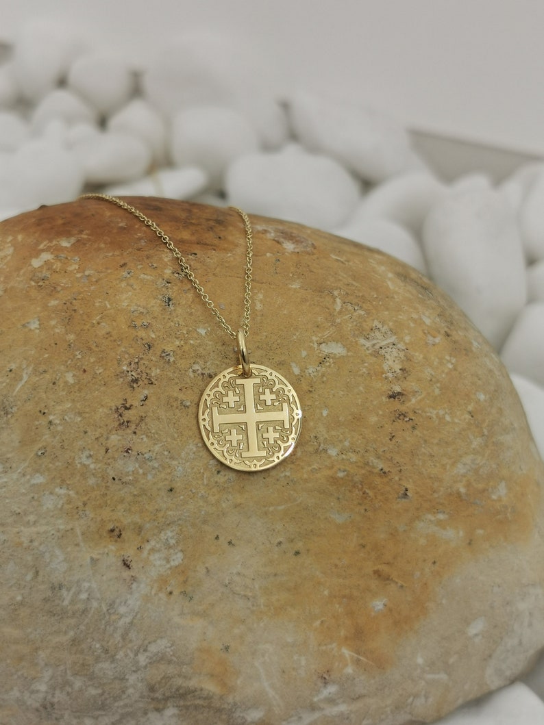 Jerusalim cross engraved, circular,
solid gold pendant 14k,
the size is 0,5 iches / 12,7 millimeter.
Thickness 0,5 milimiters.
The hoop on top is circular and gold as well.
 The finish of the pendant in shinny.