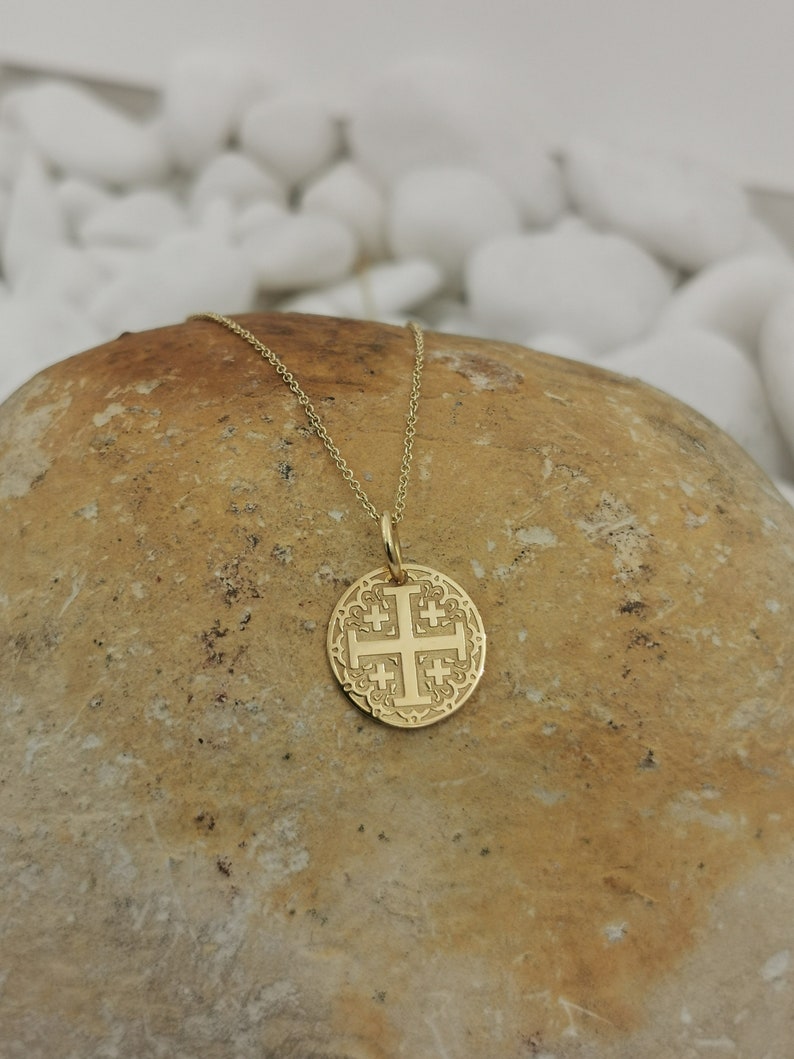 Jerusalim cross engraved, circular,
solid gold pendant 14k,
the size is 0,5 iches / 12,7 millimeter.
Thickness 0,5 milimiters.
The hoop on top is circular and gold as well.
 The finish of the pendant in shinny.