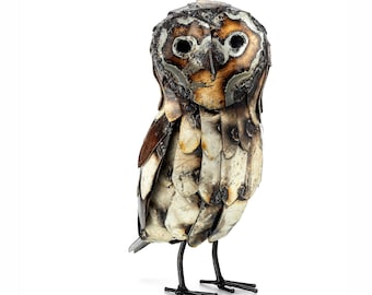 May include: A metal owl sculpture painted in brown, white and silver. The owl has large, round eyes and is standing on two legs.