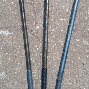 May include: Three wooden staffs with different coloured tips and decorative wraps. The staffs are wrapped in black, silver, and blue tape. The tips are green, blue, and gold.