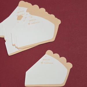 May include: A stack of pie-shaped cards with a light brown crust and white center. The cards have the text "a piece of advice" in a light brown script. The background is a solid maroon color.