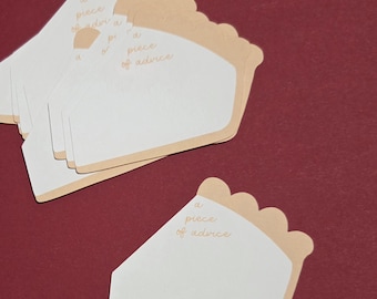 May include: A stack of pie-shaped cards with a light brown crust and white center. The cards have the text "a piece of advice" in a light brown script. The background is a solid maroon color.