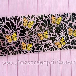 May include: A clear stencil featuring a black floral design with yellow and orange butterflies. The stencil is held against a pink background. The website address www.fmzscreenprints.com is printed at the bottom.