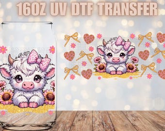 May include: A 16oz UV DTF transfer featuring a cute cartoon cow with pink and white spots wearing a pink bow. The cow is surrounded by pink and yellow flowers and hearts.