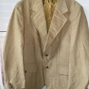May include: A beige corduroy blazer with a gold satin lining. The blazer has a single-breasted closure with three buttons and two flap pockets.