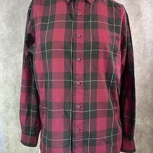 Puede incluir: Una camisa de manga larga con botones y un estampado de cuadros negros y burdeos.