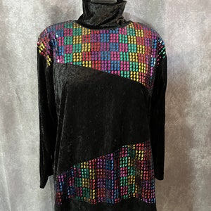 Pode incluir: Top de veludo preto de gola alta com um design diagonal de lantejoulas coloridas. As lantejoulas estão dispostas em um padrão geométrico.
