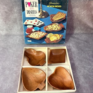 May include: A set of four brown acacia wood snack dishes shaped like playing card suits, including a heart, diamond, club, and spade, presented in a white cardboard box with a blue box cover featuring the text Poker Mini Dishes.
