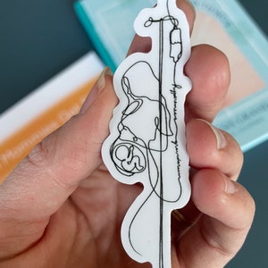 Puede incluir: Una pegatina blanca con un dibujo de línea negra de una persona embarazada conectada a un goteo intravenoso. El texto "hyperemesis gravidarum" está escrito a lo largo de la línea IV.