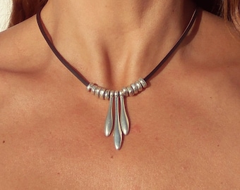 May include: A silver necklace with a black leather cord and a pendant with multiple teardrop-shaped charms.