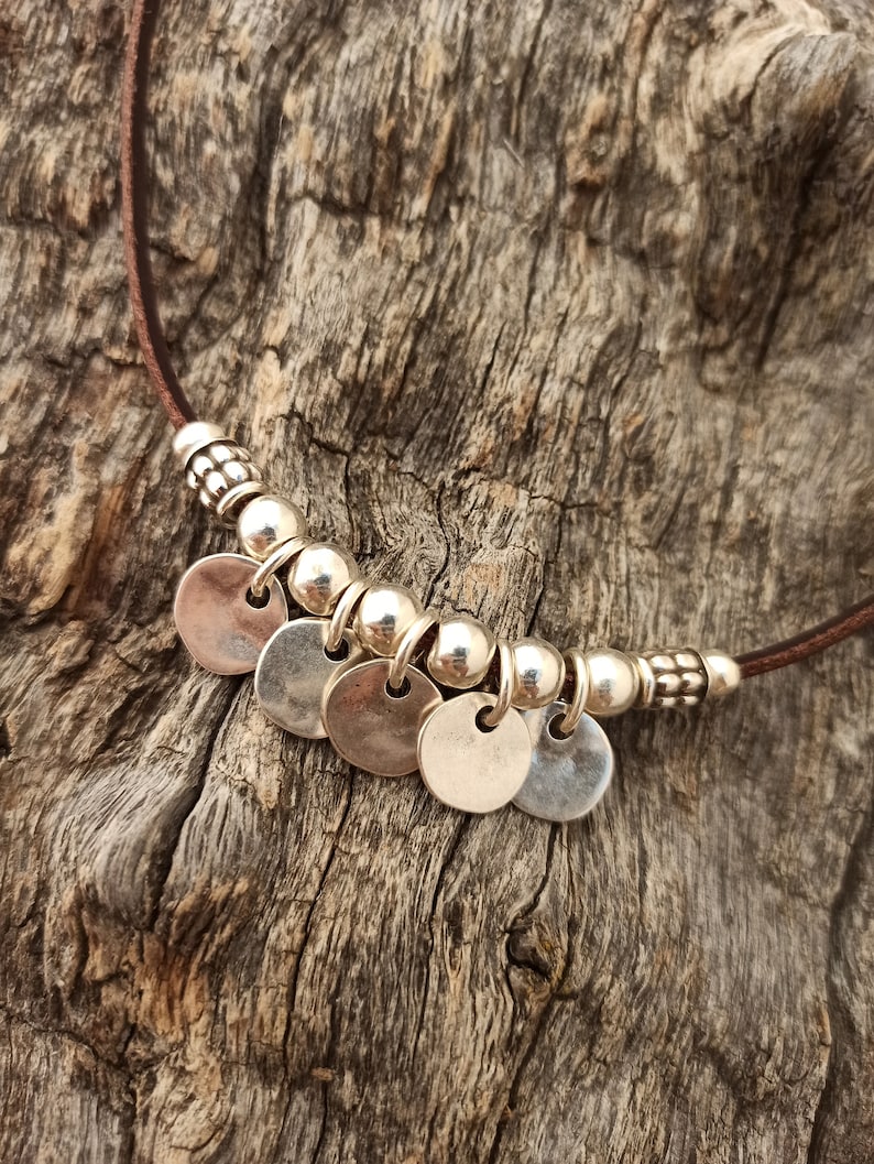 May include: A brown leather necklace with silver round charms and beads.