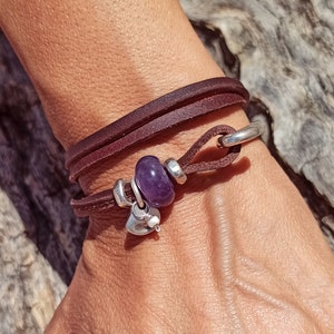 Peut inclure: Un bracelet en cuir marron avec une fermeture en crochet argenté et un charme en améthyste violette. Le charme est attaché à un pendentif en forme de cœur argenté.