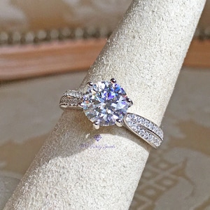 May include: A silver ring with a large, round, clear center stone and a double row of smaller stones on the band.