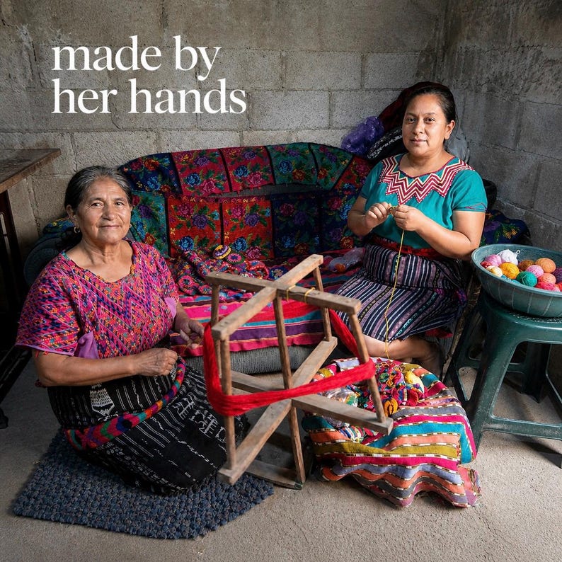 Peut inclure: Deux femmes sont assises, l'une tenant un d&eacute;vidoir en bois avec de la laine rouge, l'autre tricotant. La sc&egrave;ne se d&eacute;roule dans une pi&egrave;ce avec un canap&eacute; &agrave; motifs floraux et le texte "made by her hands". Des boules de fil color&eacute;es sont dans un bol.