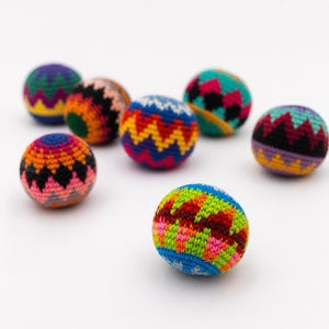 Peut inclure: Huit balles de hacky sack tricot&eacute;es &agrave; la main, aux couleurs vives. Chaque balle pr&eacute;sente un motif unique avec des couleurs comme le bleu, le vert, le rouge, le jaune et le violet. Les balles sont rondes et semblent remplies d'une mati&egrave;re souple.