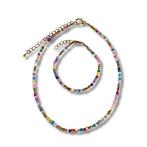 May include: A set of two colorful beaded necklaces, one longer than the other, with gold accents. The necklaces are made of small, colorful beads and have a delicate, feminine look.