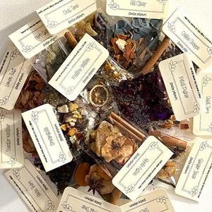 May include: A collection of small, clear bags filled with various dried fruits, spices, and herbs. Each bag has a label with a different name, such as "Coffee Shoppe", "Petal Pusher", and "Mellow Yellow".