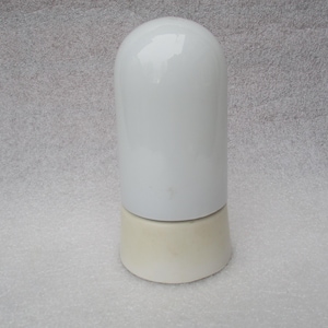 Puede incluir: Objeto de cerámica blanca con parte superior redondeada y base cilíndrica. La parte superior es blanca brillante, la base es de color blanquecino mate. Probablemente un artículo decorativo o parte de un conjunto. Medidas en centímetros.