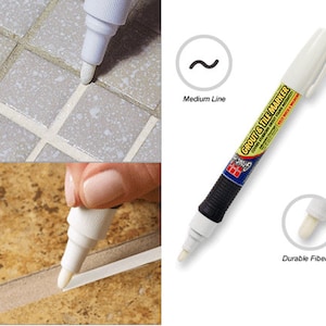 May include: White grout and tile marker pen with a durable fiber tip. The marker is used to draw a medium line on a white tile surface. The text on the marker reads "Grout & Tile Marker".